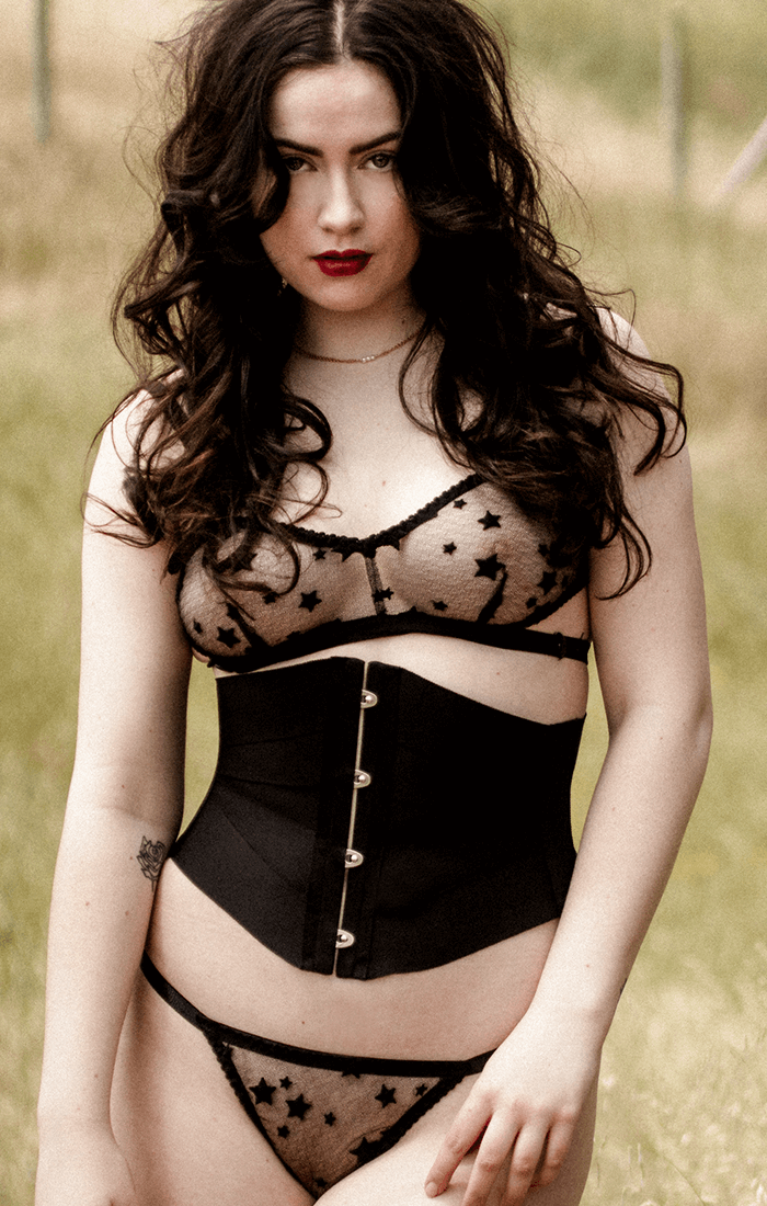 Black ribbon corset worn with fine lace lingerie in sheer black lace with stars