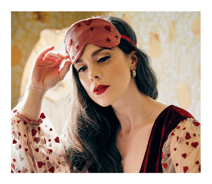 Red silk sleep mask with embroidered heart lace worn with luxury velvet robe